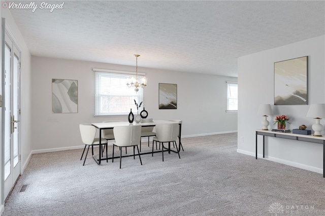 carpeted dining room with a textured ceiling and a notable chandelier