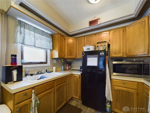 kitchen featuring dark hardwood / wood-style flooring, black refrigerator, sink, and a textured ceiling