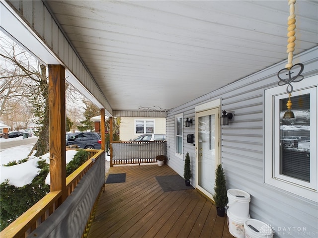 snow covered deck featuring a porch