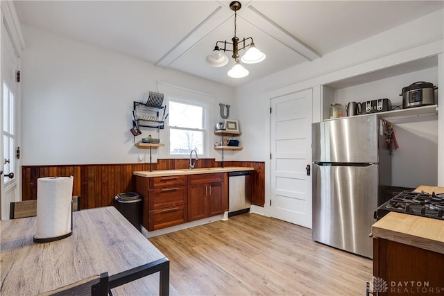 kitchen featuring appliances with stainless steel finishes, decorative light fixtures, light hardwood / wood-style floors, and sink