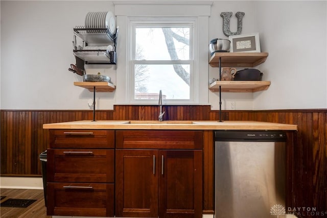 bar with hardwood / wood-style flooring, sink, stainless steel dishwasher, and wood walls