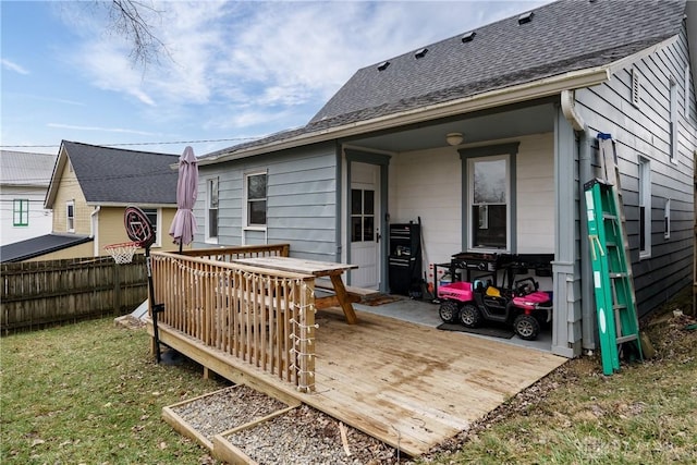 back of property featuring a deck and a lawn