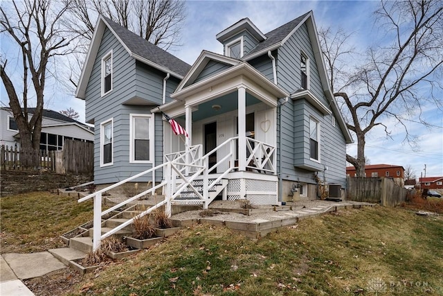 view of front facade featuring a porch, a front yard, and central air condition unit