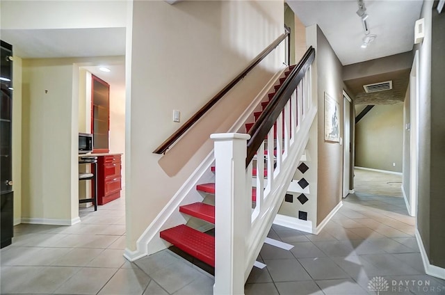 stairs with track lighting and tile patterned flooring