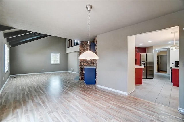 unfurnished dining area featuring a stone fireplace, light hardwood / wood-style flooring, and lofted ceiling with beams