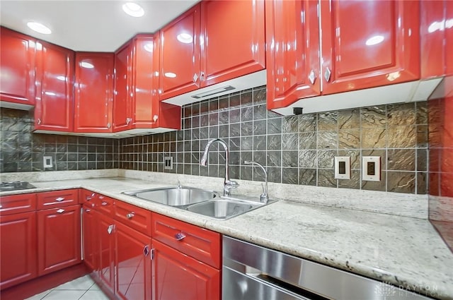 kitchen with light tile patterned flooring, sink, stainless steel dishwasher, and light stone counters