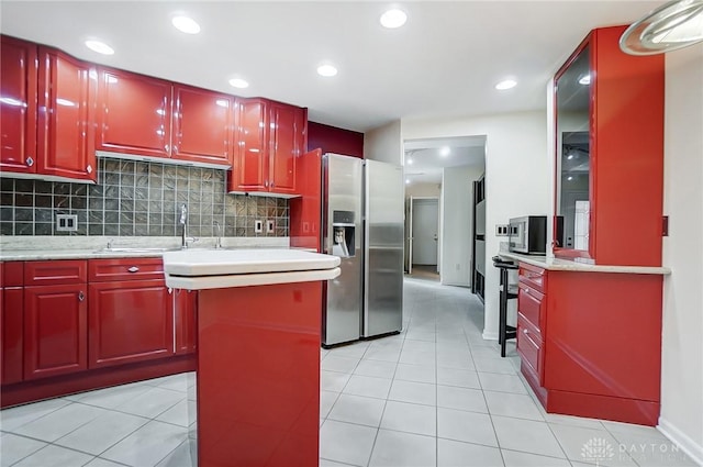 kitchen with decorative backsplash, stainless steel fridge with ice dispenser, a kitchen island, and light tile patterned floors