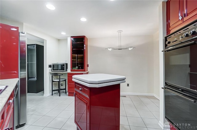 kitchen featuring light tile patterned flooring, a kitchen island, double oven, decorative light fixtures, and fridge