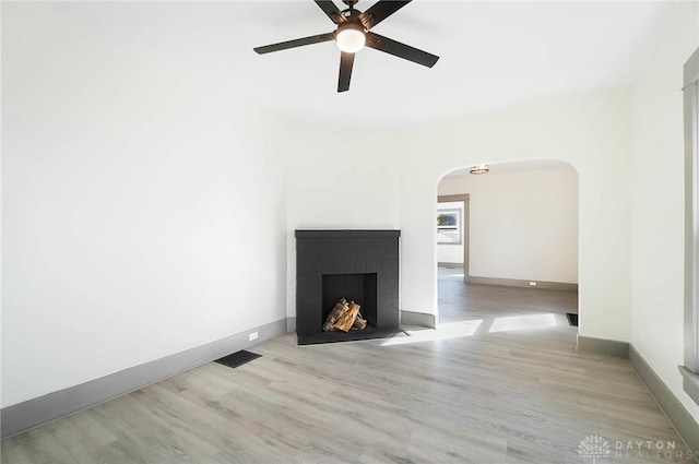 unfurnished living room featuring ceiling fan, a fireplace, and light wood-type flooring