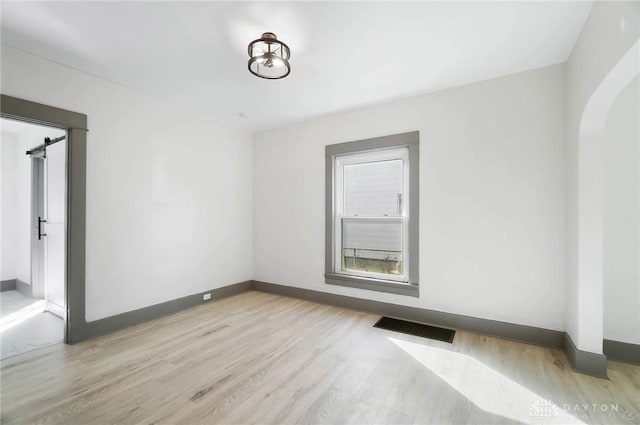 empty room featuring a barn door and light wood-type flooring