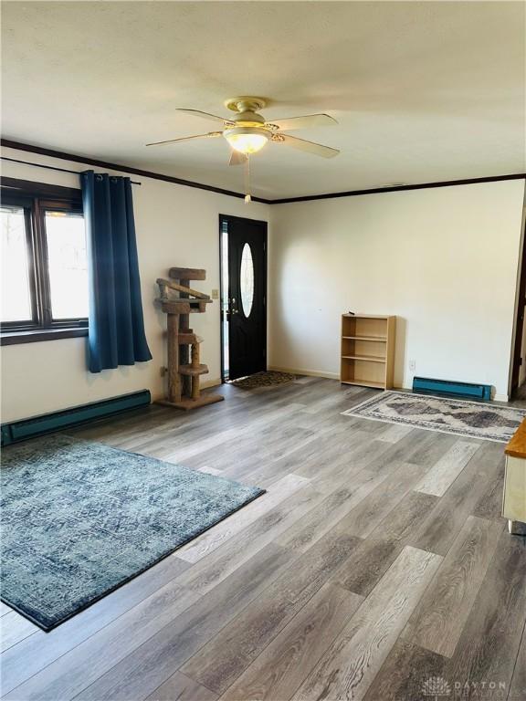 entrance foyer with ceiling fan, a baseboard radiator, ornamental molding, and hardwood / wood-style floors