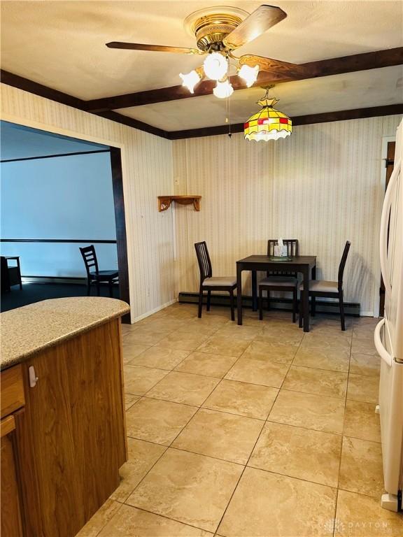 dining space with light tile patterned floors, beamed ceiling, and ceiling fan