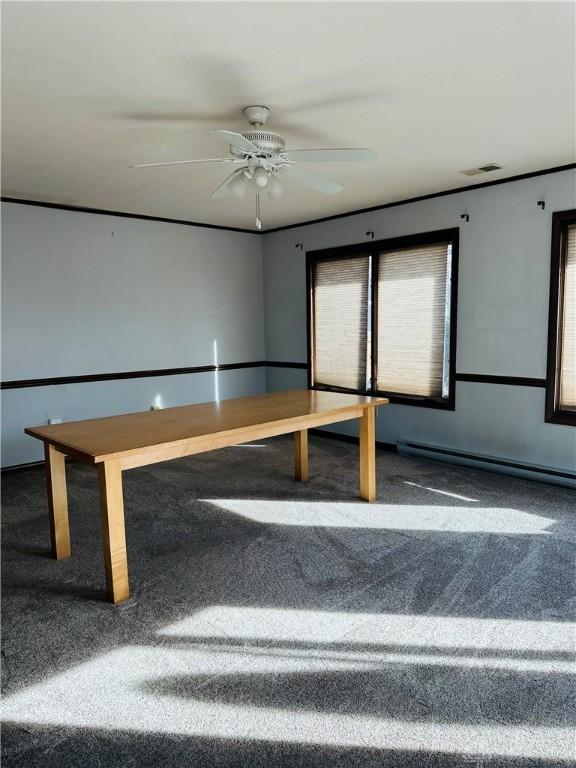 interior space with dark colored carpet, a baseboard heating unit, and ceiling fan