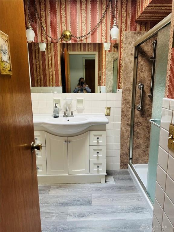 bathroom with vanity, hardwood / wood-style flooring, tile walls, and walk in shower