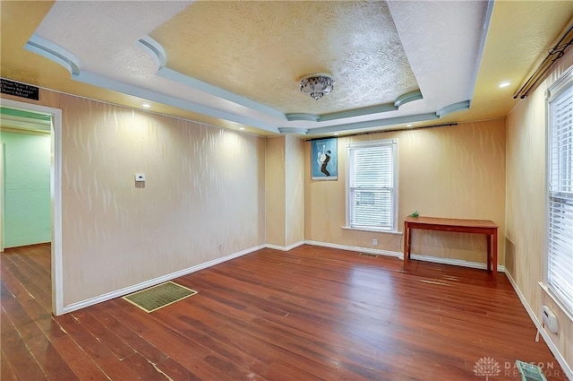 spare room with dark hardwood / wood-style floors, a raised ceiling, and a textured ceiling