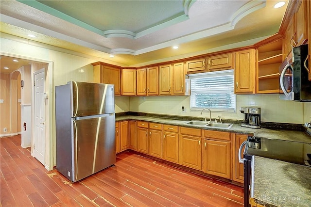 kitchen with sink, tasteful backsplash, wood-type flooring, a tray ceiling, and stainless steel appliances