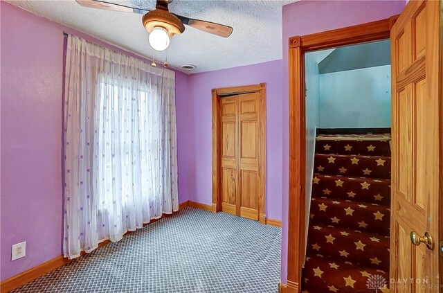 unfurnished bedroom with ceiling fan, a closet, carpet, and a textured ceiling