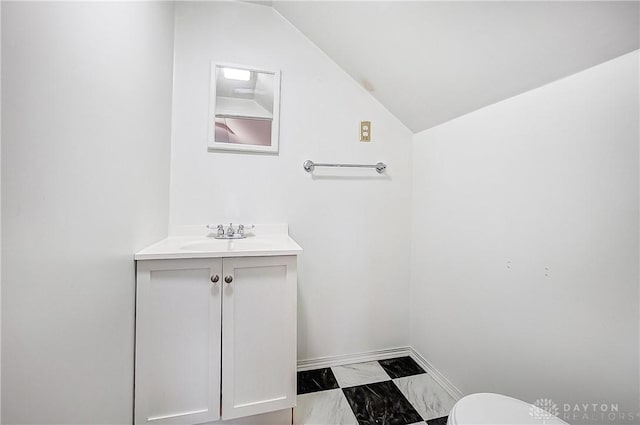 bathroom featuring vanity, lofted ceiling, and toilet