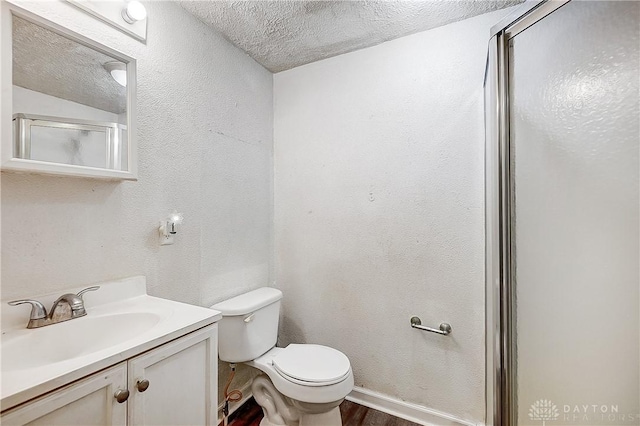 bathroom featuring a shower with shower door, wood-type flooring, vanity, toilet, and a textured ceiling