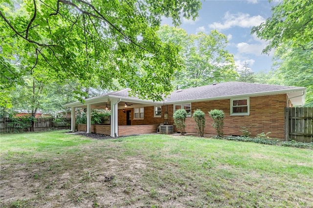 rear view of property featuring cooling unit, ceiling fan, and a yard