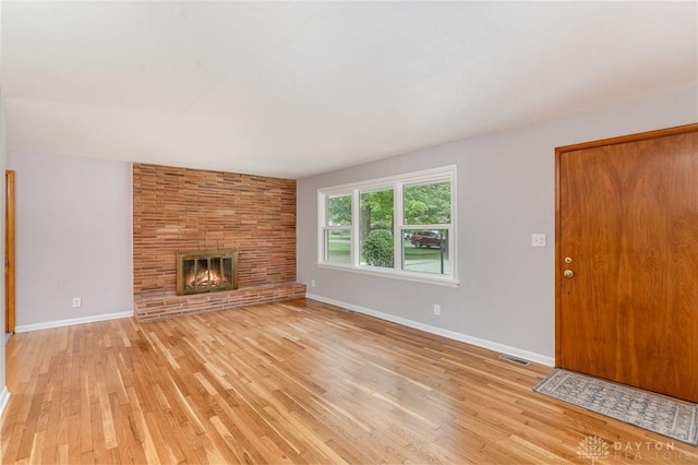 unfurnished living room featuring a large fireplace and light wood-type flooring