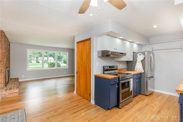 kitchen with butcher block counters, appliances with stainless steel finishes, a fireplace, light hardwood / wood-style floors, and white cabinets