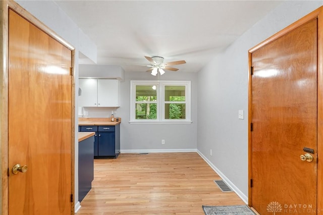 kitchen featuring ceiling fan, light hardwood / wood-style floors, and white cabinets