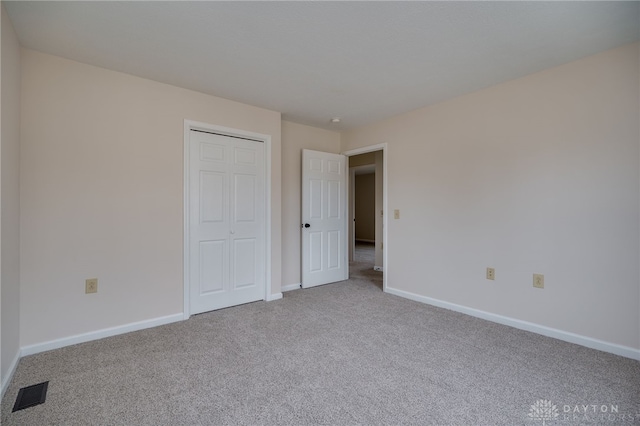 unfurnished bedroom with light carpet and a closet