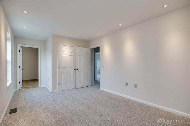 unfurnished bedroom with light carpet and a closet