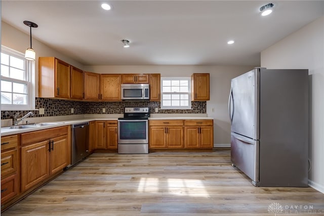 kitchen with backsplash, decorative light fixtures, light hardwood / wood-style flooring, and appliances with stainless steel finishes