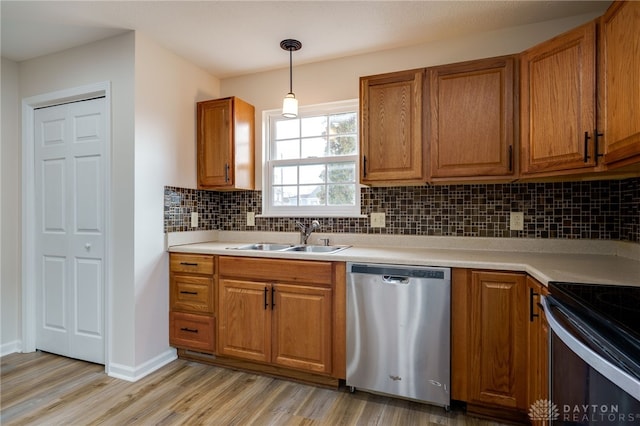 kitchen featuring decorative light fixtures, dishwasher, sink, decorative backsplash, and light wood-type flooring