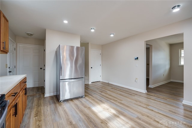 kitchen with stainless steel fridge and light hardwood / wood-style floors