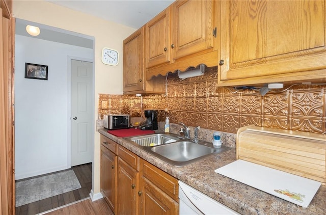 kitchen featuring sink, dark wood-type flooring, white dishwasher, and decorative backsplash