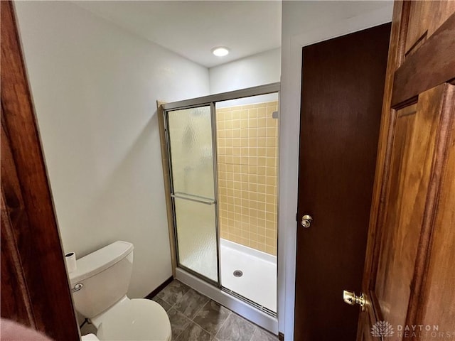 bathroom featuring toilet and a shower with door