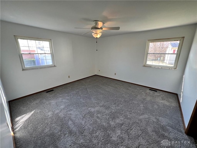 spare room featuring dark colored carpet, plenty of natural light, and ceiling fan