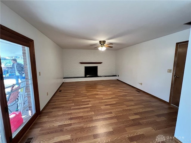 unfurnished living room with ceiling fan, dark hardwood / wood-style flooring, and a brick fireplace