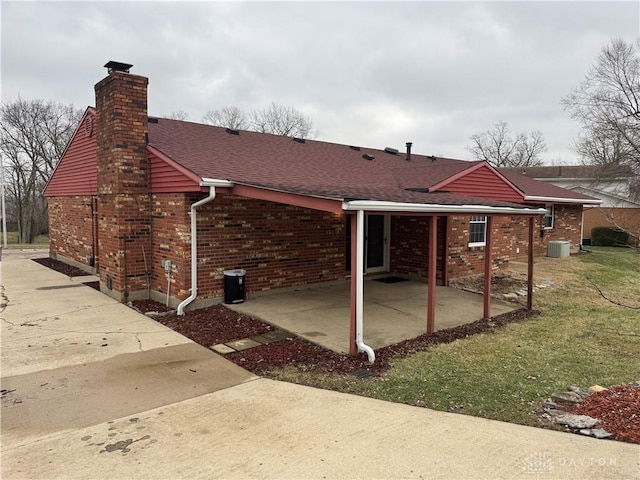 rear view of house featuring cooling unit, a lawn, and a patio