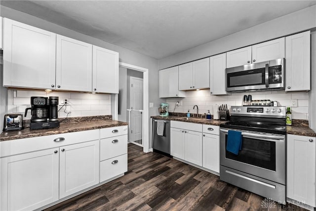 kitchen with sink, appliances with stainless steel finishes, dark hardwood / wood-style floors, white cabinets, and decorative backsplash