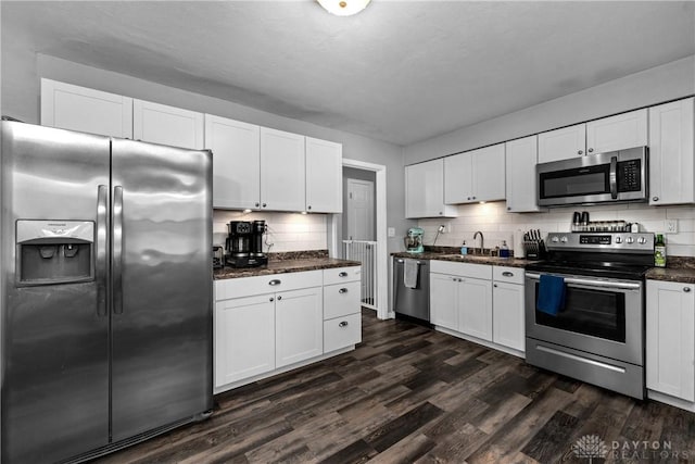 kitchen featuring white cabinetry, stainless steel appliances, dark hardwood / wood-style flooring, and backsplash