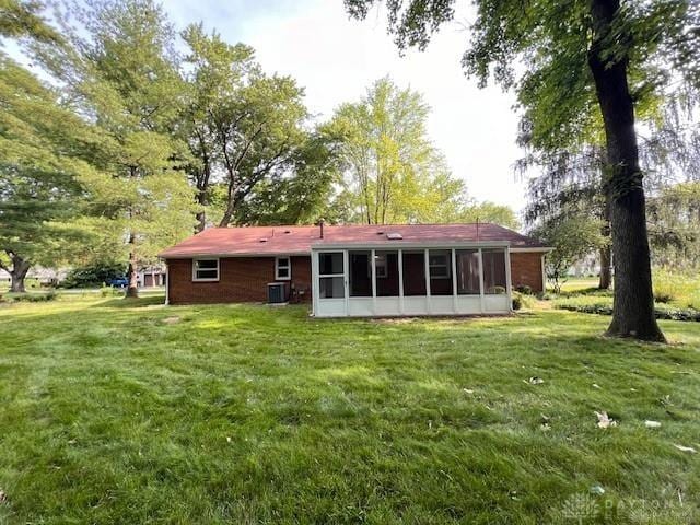 rear view of house featuring a lawn and a sunroom