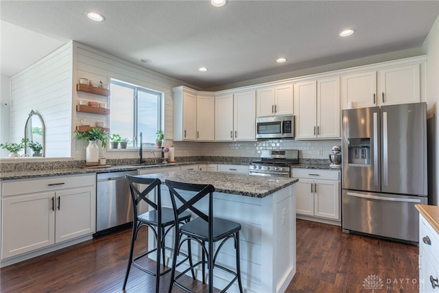 kitchen featuring white cabinetry, appliances with stainless steel finishes, dark hardwood / wood-style flooring, and dark stone counters