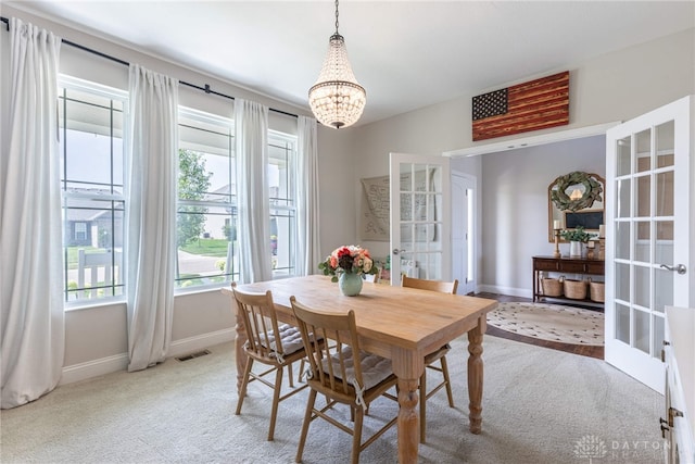 dining room with carpet flooring, a chandelier, and french doors