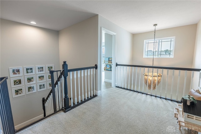 corridor featuring an inviting chandelier and carpet