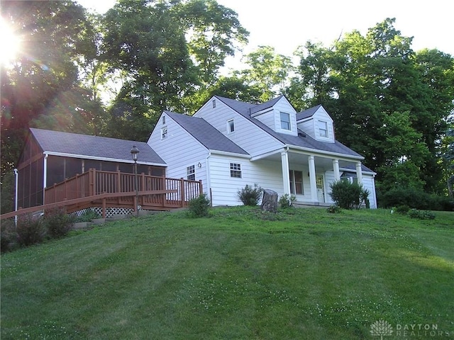 back of property with a lawn, a sunroom, and a deck