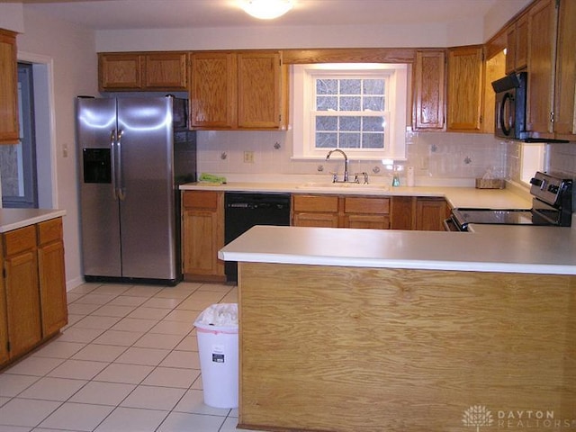 kitchen featuring sink, light tile patterned floors, black appliances, and kitchen peninsula