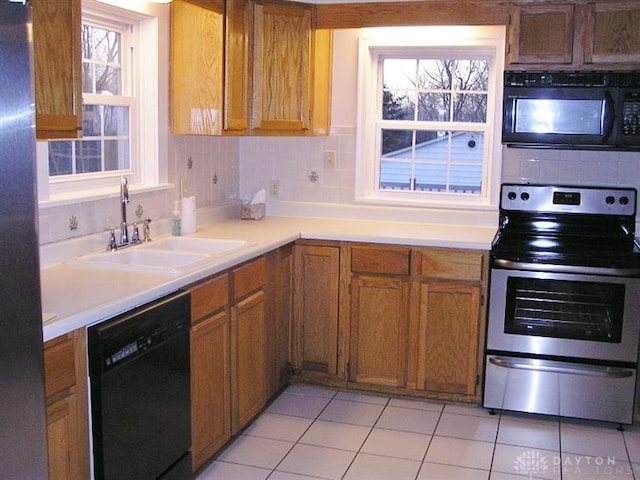 kitchen with stainless steel appliances, sink, light tile patterned floors, and decorative backsplash