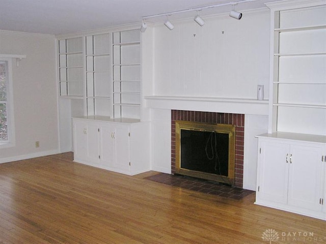 unfurnished living room with crown molding, a brick fireplace, and hardwood / wood-style flooring