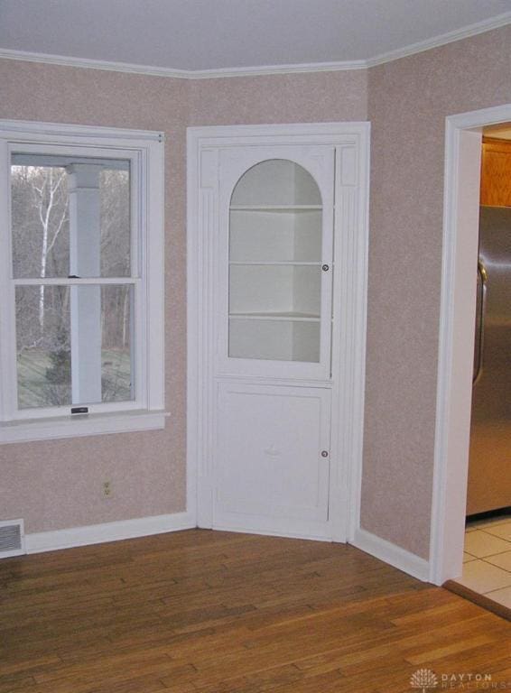 interior space featuring crown molding, dark wood-type flooring, and a healthy amount of sunlight