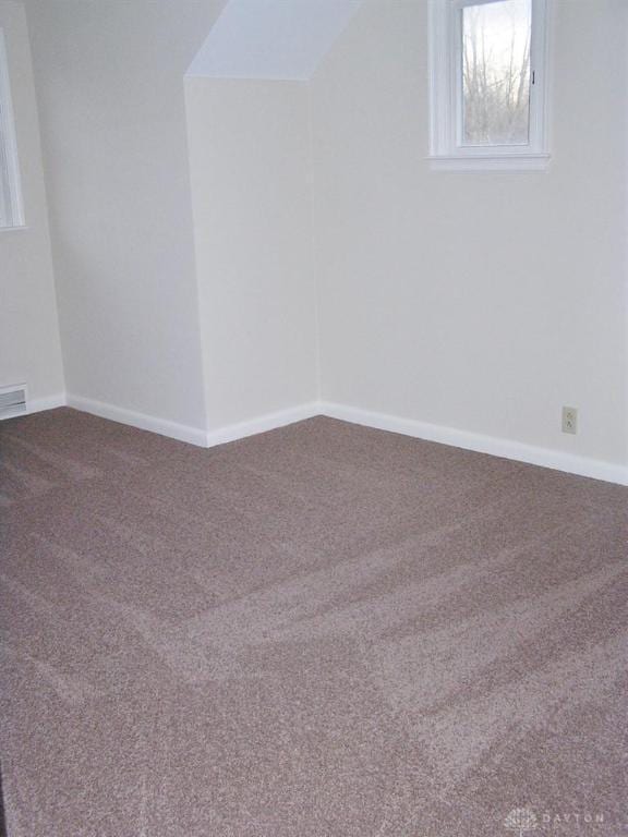 empty room featuring vaulted ceiling and carpet floors