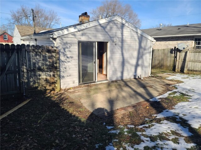 snow covered back of property featuring a patio